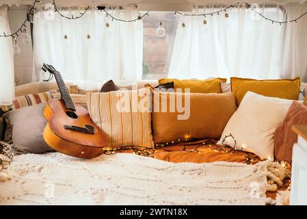 Intérieur de chambre confortable inspiré par les couleurs de l'automne. Oreillers, lit léger d'un mobil-home sur roues. Ampoules électriques. Banque D'Images