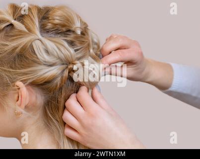 Belle fille blonde avec une belle coiffure soignée, gros plan dans un salon de beauté. Soins capillaires professionnels et création de coiffures. Banque D'Images