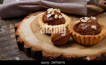 muffins au chocolat sucré et biscuits noix avec du lait condensé sur un support en bois avec toile de jute sur la table. nature morte. Banque D'Images