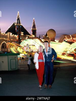 Australie. North Sydney. Foire funfair de Luna Park la nuit. Jeune couple marchant. Banque D'Images