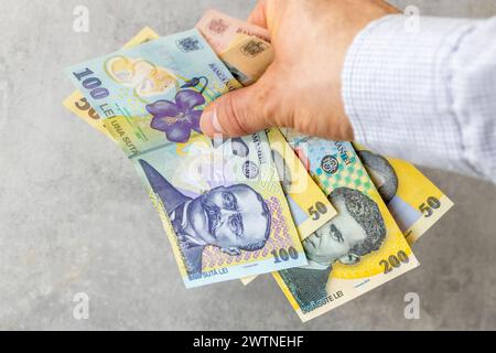 Roumanie argent, homme d'affaires met une poignée de billets de banque lei roumains sur une table grise, Business et concept économique, finances roumaines, espace de copie Banque D'Images