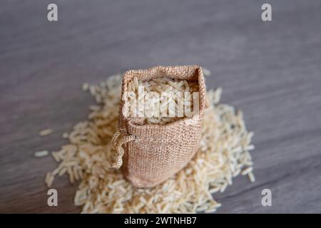 Gros plan image de riz brun dans un petit sac en toile de jute sur une table en bois avec espace de copie. Banque D'Images