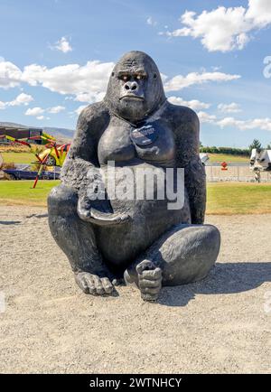 Cromwell, Nouvelle-Zélande- 3 janvier 2024 : sculpture de gorille noire se trouve à Highlands, Cromwell, NZ, avec des voitures de course et un ciel clair en arrière-plan. Banque D'Images