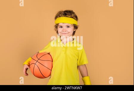 Sport pour enfants. Petit joueur de basket-ball en uniforme sportif avec ballon. Concept de sport hobby. Fitness, entraînement et mode de vie sain. Mignon sportif Banque D'Images