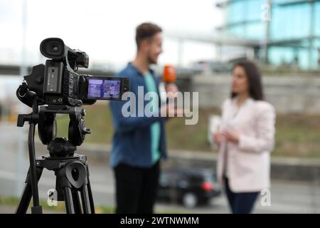 Jeune journaliste interviewant femme d'affaires dans la rue de ville, se concentrer sur l'affichage de caméra Banque D'Images