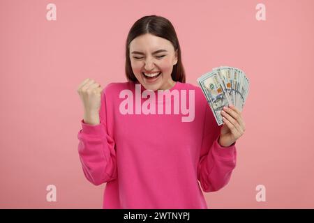 Femme heureuse avec des billets de banque en dollars sur fond rose Banque D'Images