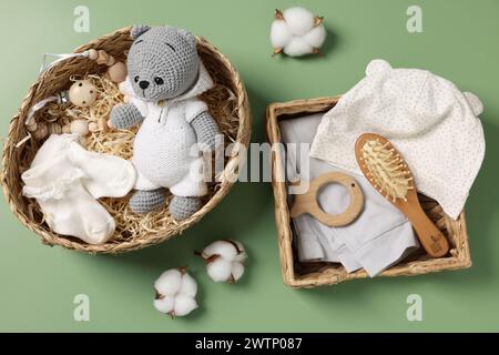 Différents accessoires pour bébé, vêtements et fleurs de coton sur fond vert, plat Banque D'Images