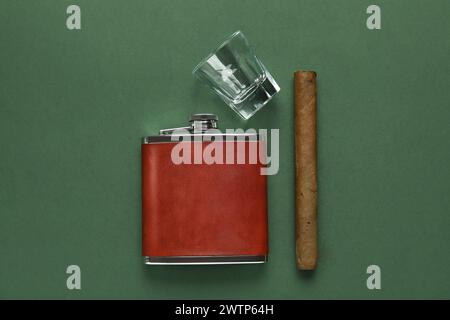 Nouveau flacon de hanche, verre et cigare sur fond vert Banque D'Images