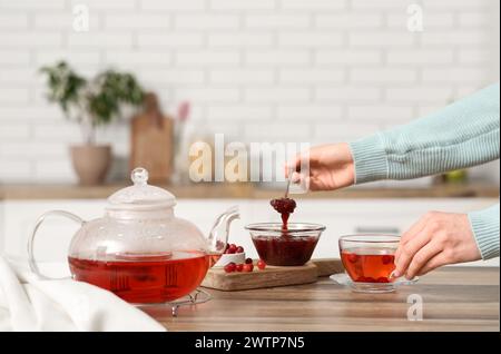 Jeune femme faisant du thé avec de la confiture de canneberges dans la cuisine Banque D'Images