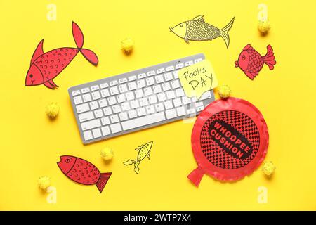 Clavier d'ordinateur, note collante et coussin whoopee sur fond jaune. Farce du jour des fous d'avril Banque D'Images