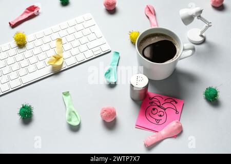 Clavier d'ordinateur, note collante, sel et tasse de café sur fond blanc. Farce du jour des fous d'avril Banque D'Images