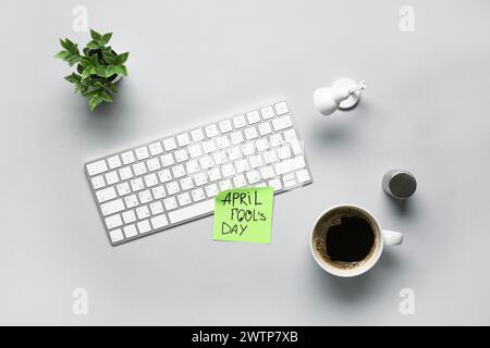Clavier d'ordinateur, note collante, sel et tasse de café sur fond blanc. Farce du jour des fous d'avril Banque D'Images