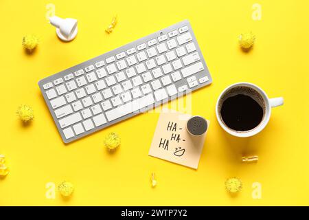 Clavier d'ordinateur, note collante, sel et tasse de café sur fond jaune. Farce du jour des fous d'avril Banque D'Images