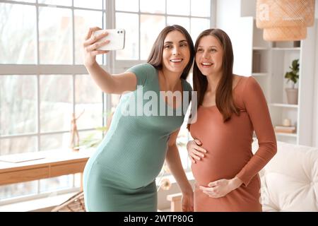 Amies enceintes prenant selfie à la maison Banque D'Images