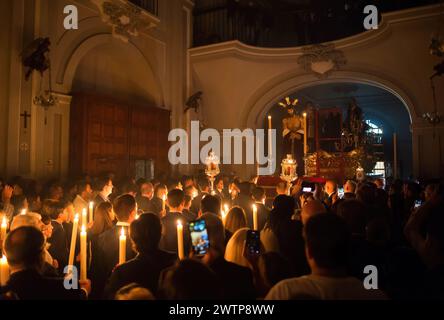 Malaga, Espagne. 18 mars 2024. Des pénitents de la confrérie Humildad sont vus tenant des bougies devant la statue du Christ après le transfert du cloître à l'intérieur du Santuario de la Victoria. Au cours des dernières semaines, des dizaines de confréries portent leurs icônes dans leurs églises, suivant les rituels traditionnels entourés par la lumière des bougies. (Photo de Jesus Merida/SOPA images/SIPA USA) crédit : SIPA USA/Alamy Live News Banque D'Images