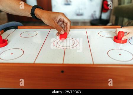 Deux individus se sont engagés dans une partie de hockey pneumatique, frappant habilement la rondelle avec des pagaies sur une surface de table lisse. Banque D'Images