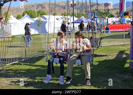 Deux jeunes filles faisant un tour à la foire de l'État de l'Utah avec les montagnes en arrière-plan. Banque D'Images