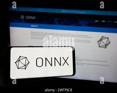 Personne tenant un smartphone avec le logo de l'écosystème ai Open Neural Network Exchange (ONNX) devant le site Web. Concentrez-vous sur l'affichage du téléphone. Banque D'Images