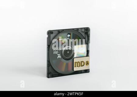 Un minidisc avec un volet de protection ouvert et un reflet arc-en-ciel de la surface du disque est isolé sur un fond blanc. Banque D'Images