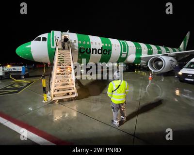 Plan de nuit de l'avion Condor Airbus A321 debout atterri en position de stationnement sur l'aire de trafic de l'aéroport avec des escaliers mobiles pour les passagers Banque D'Images