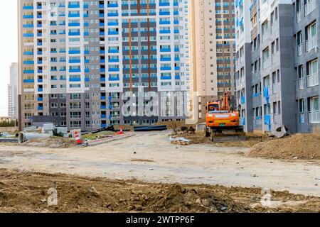 Excavatrice orange sur un chemin de terre avec des immeubles de grande hauteur nouvellement construits, à Daejeon, Corée du Sud Banque D'Images