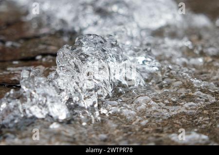 Le tuyau d'eau éclate, l'eau coule hors du trou d'homme sur l'asphalte. L'accident dans l'égout. Fuite du système d'alimentation en eau dans la ville sur le Banque D'Images