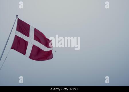 Une photo à angle bas d'un drapeau danois soufflant dans le vent par une journée fraîche Banque D'Images