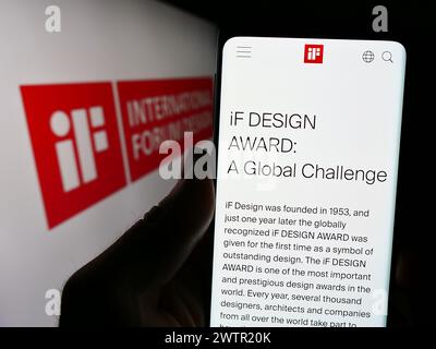 Personne tenant un smartphone avec la page web de l'organisation allemande International Forum Design (IF) devant le logo. Concentrez-vous sur le centre de l'écran du téléphone. Banque D'Images