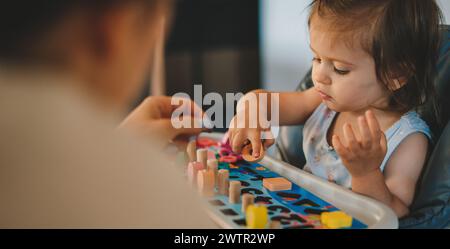 Portrait petite fille heureuse jouant activité de compétence d'entraînement de cerveau jouer avec jouet construire des blocs en bois jeu d'éducation de plateau. Pièce de puzzle correcte dans Banque D'Images