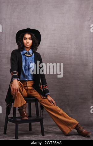 Portrait, cowgirl ou femme en studio, culture de l'Ouest sauvage et mode cool dans les vêtements sur fond gris. Jeune femme, femme occidentale et élégant Banque D'Images