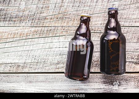 Deux bouteilles en verre brun remplies de bière sont placées soigneusement sur une table en bois. Banque D'Images