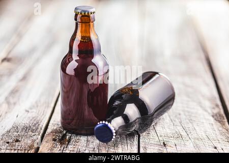Deux bouteilles en verre brun remplies de bière sont placées sur une table en bois. Banque D'Images