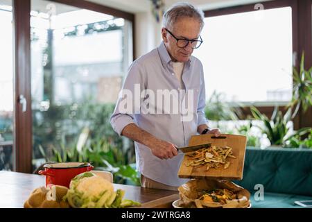 Homme mûr fabriquant du compost à partir de restes à la maison Banque D'Images