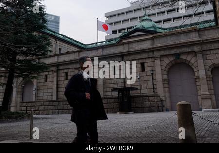 Tokyo, Japon. 19 mars 2024. Un homme passe devant la Banque du Japon à Tokyo, Japon, le 19 mars 2024. Mardi, la Banque du Japon (BOJ) a décidé de mettre fin à sa politique de taux d’intérêt négatif pour sa première hausse de taux en 17 ans, marquant un changement majeur par rapport à l’assouplissement monétaire de longue date que le Japon a connu au cours de la dernière décennie pour mettre fin à la déflation. Crédit : Zhang Xiaoyu/Xinhua/Alamy Live News Banque D'Images