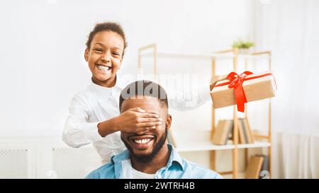 Jolie fille afro qui ferme les yeux du père et fait la surprise Banque D'Images