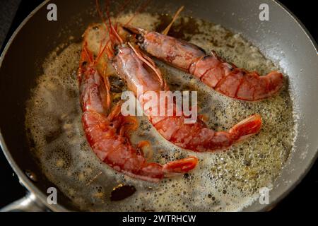 Cuisson de la langoustine sur une poêle avec du beurre et de l'ail. Banque D'Images