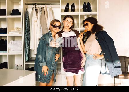 Les adolescentes charismatiques de différentes races collectent des vêtements pour la garde-robe. Les filles multiethniques prennent des selfies dans le vestiaire à la maison. Mignon frien Banque D'Images