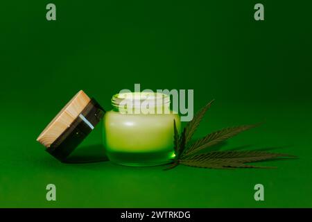 Une maquette d'une bouteille en verre transparent avec une crème avec concentré hydratant, acide hyaluronique avec couvercle et feuille de chanvre. Sérum facial dans un pot avec Banque D'Images