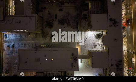 Photographie par drone de la cour arrière d'une maison à plusieurs étages dans une ville couverte par la neige pendant la nuit nuageuse d'hiver Banque D'Images