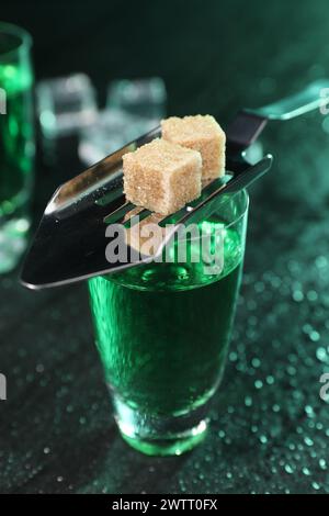 Absinthe dans le verre à grenaille, cuillère et cubes de cassonade sur la table grise, gros plan. Boisson alcoolisée Banque D'Images