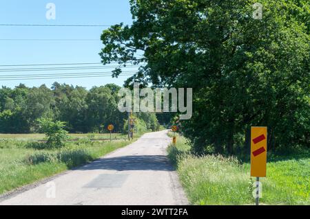 Panneaux d'avertissement sur la route approchant un passage à niveau Banque D'Images