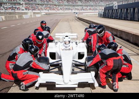 Équipe de Pit en parfaite synchronisation entretenant une voiture de course sur la piste. Banque D'Images