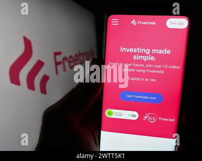Personne tenant smartphone avec la page Web de la société britannique Fintech Freetrade Ltd devant le logo de l'entreprise. Concentrez-vous sur le centre de l'écran du téléphone. Banque D'Images