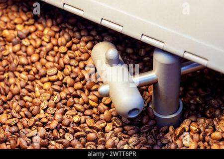 Le processus de torréfaction des grains de café consiste à mélanger des grains de café crus torréfiant ceux-ci dans une machine à four Banque D'Images