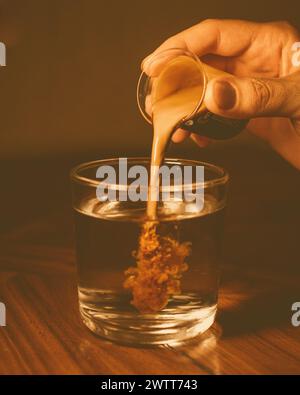 Une personne versant du café expresso dans un bocal en verre sur une table Banque D'Images