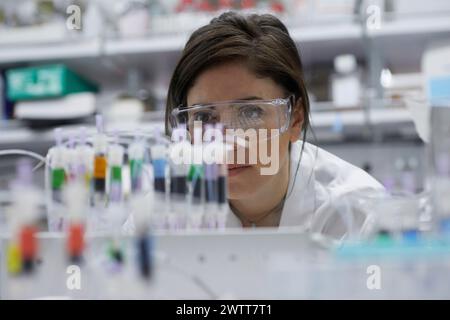 Une scientifique attirante examine un tube à essai pour obtenir des résultats Banque D'Images