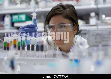 Une scientifique attirante examine un tube à essai pour obtenir des résultats Banque D'Images