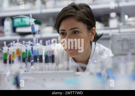 Une scientifique attirante examine un tube à essai pour obtenir des résultats Banque D'Images