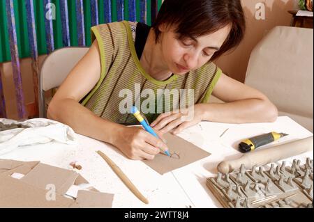 Artiste immergée dans l'artisanat avec de l'argile et des outils sur sa table d'atelier. Banque D'Images