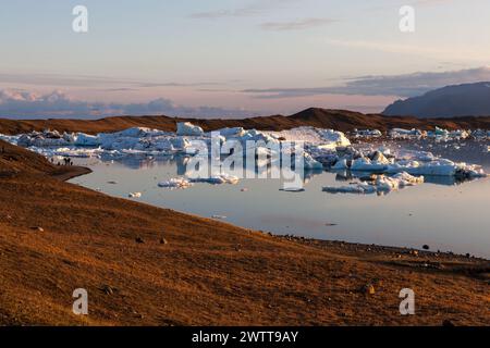 Coucher de soleil rose sur les icebergs en fusion près de la rive de la lagune glaciaire de Jokulsarlon. Nuages reflétant dans l'eau. Réchauffement planétaire et changement climatique concept Wit Banque D'Images